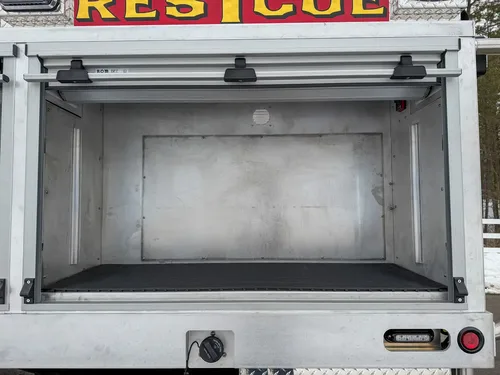 Wide open storage bay with two shelves and interior lighting.